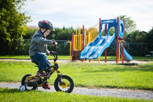 Enfant sur sa bicyclette devant des structures de jeux