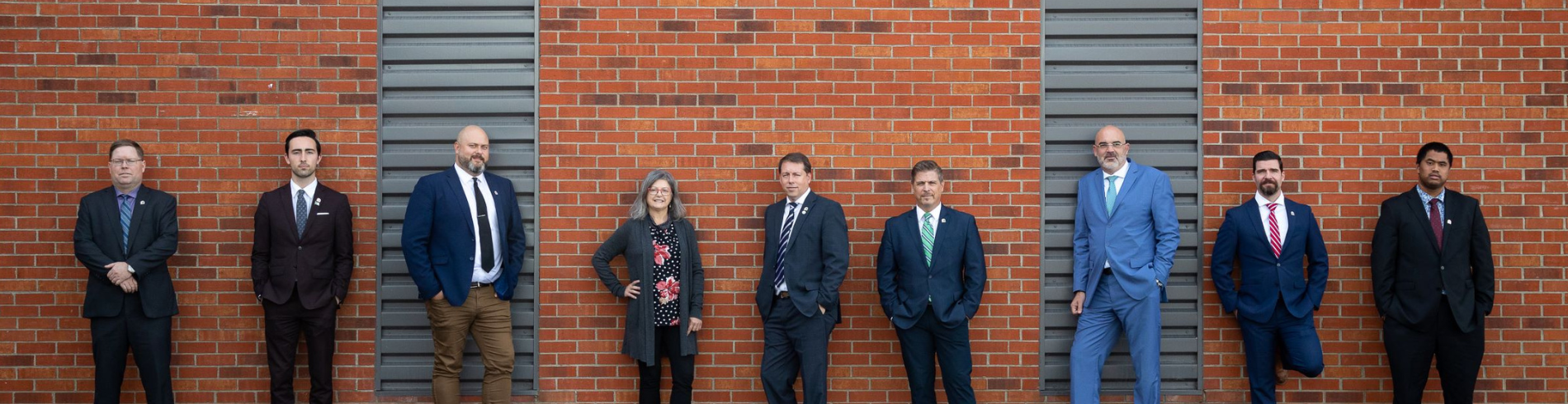 Council members standing next to a brick wall