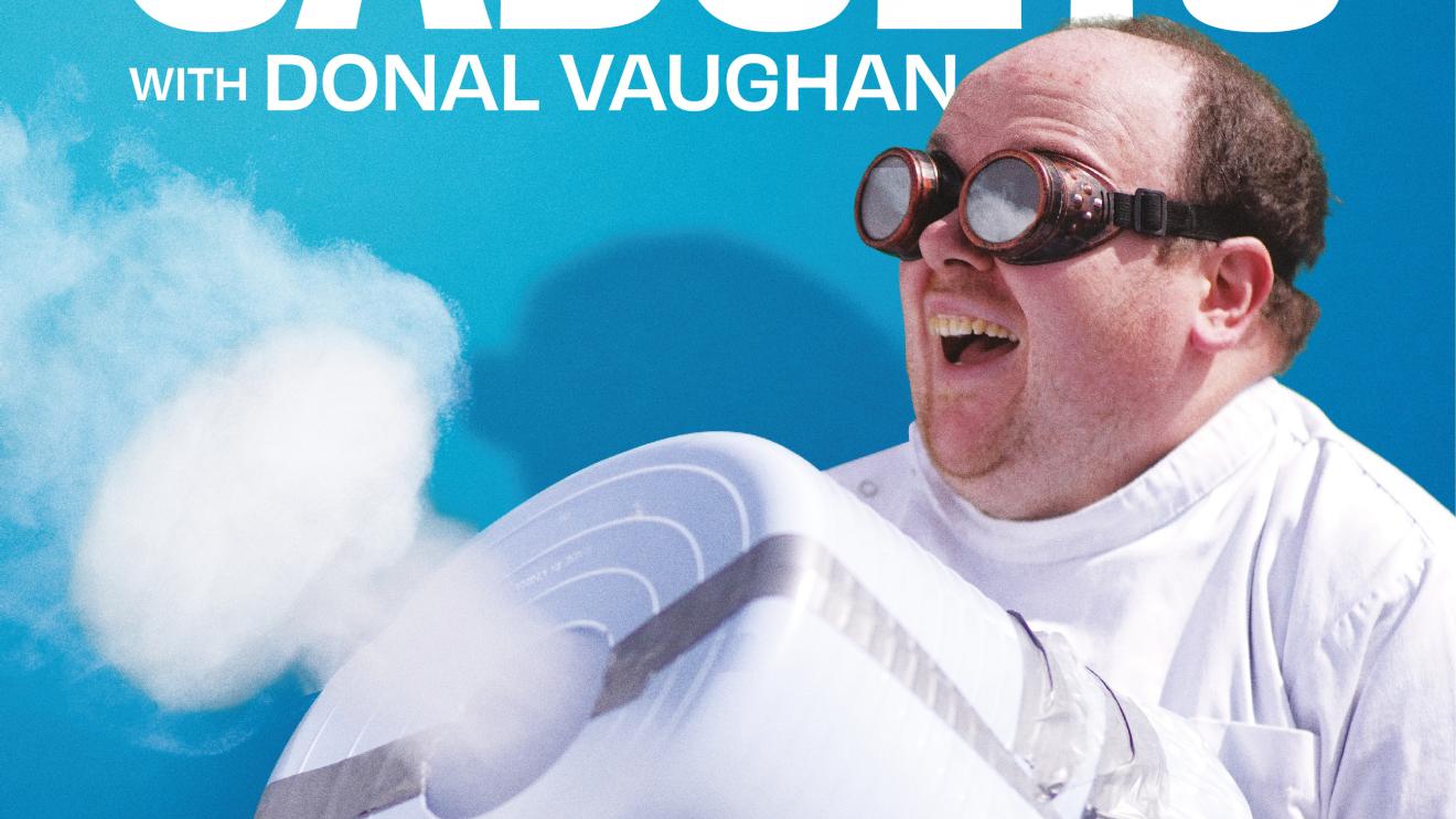 Man wearing goggles, holding a fog machine, under a blue sky background.