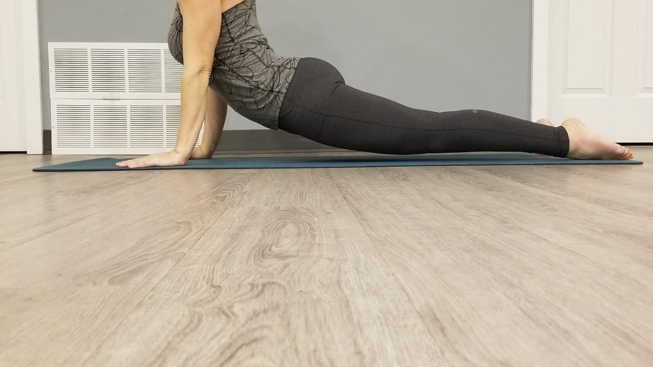 Woman practicing yoga in upward dog pose in a room.