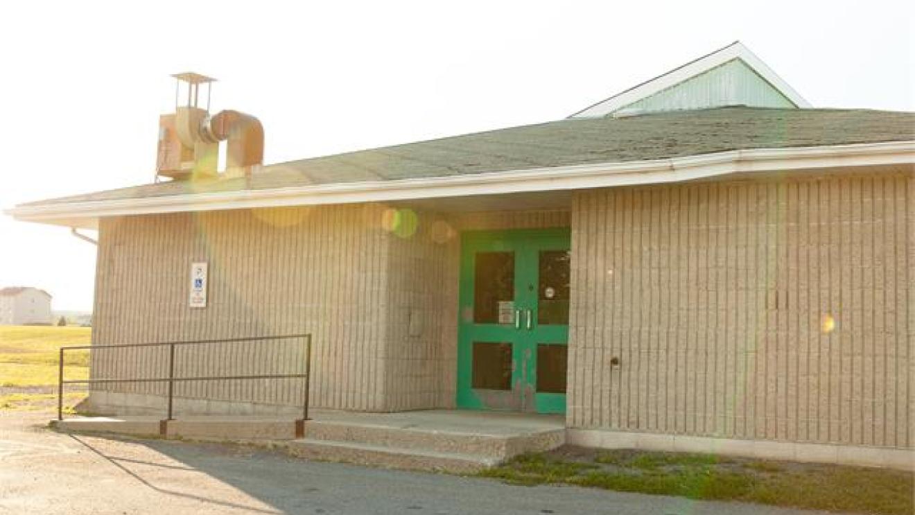 Small building with teal doors, sunlight lens flare.