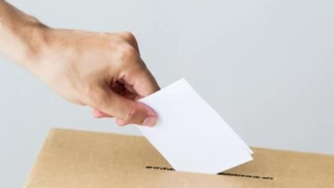 Hand placing a white paper into a cardboard box slot.