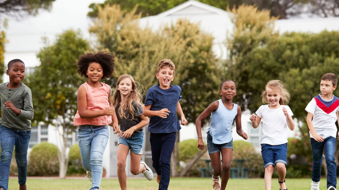 Children running on grass, trees in the background.