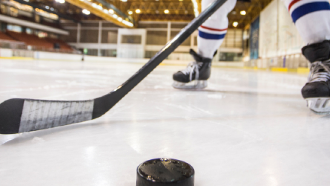 Hockey player and puck on ice rink.