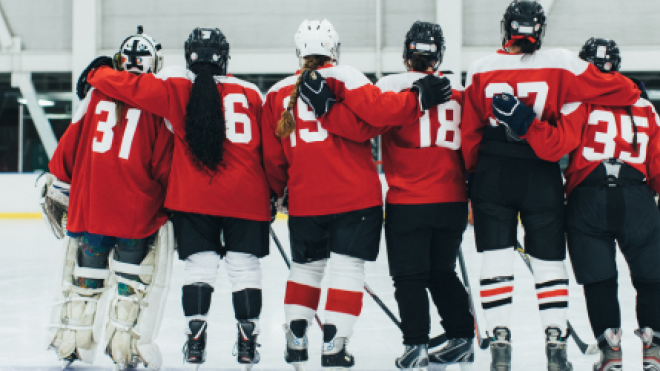 Hockey team in red jerseys huddling on ice rink.