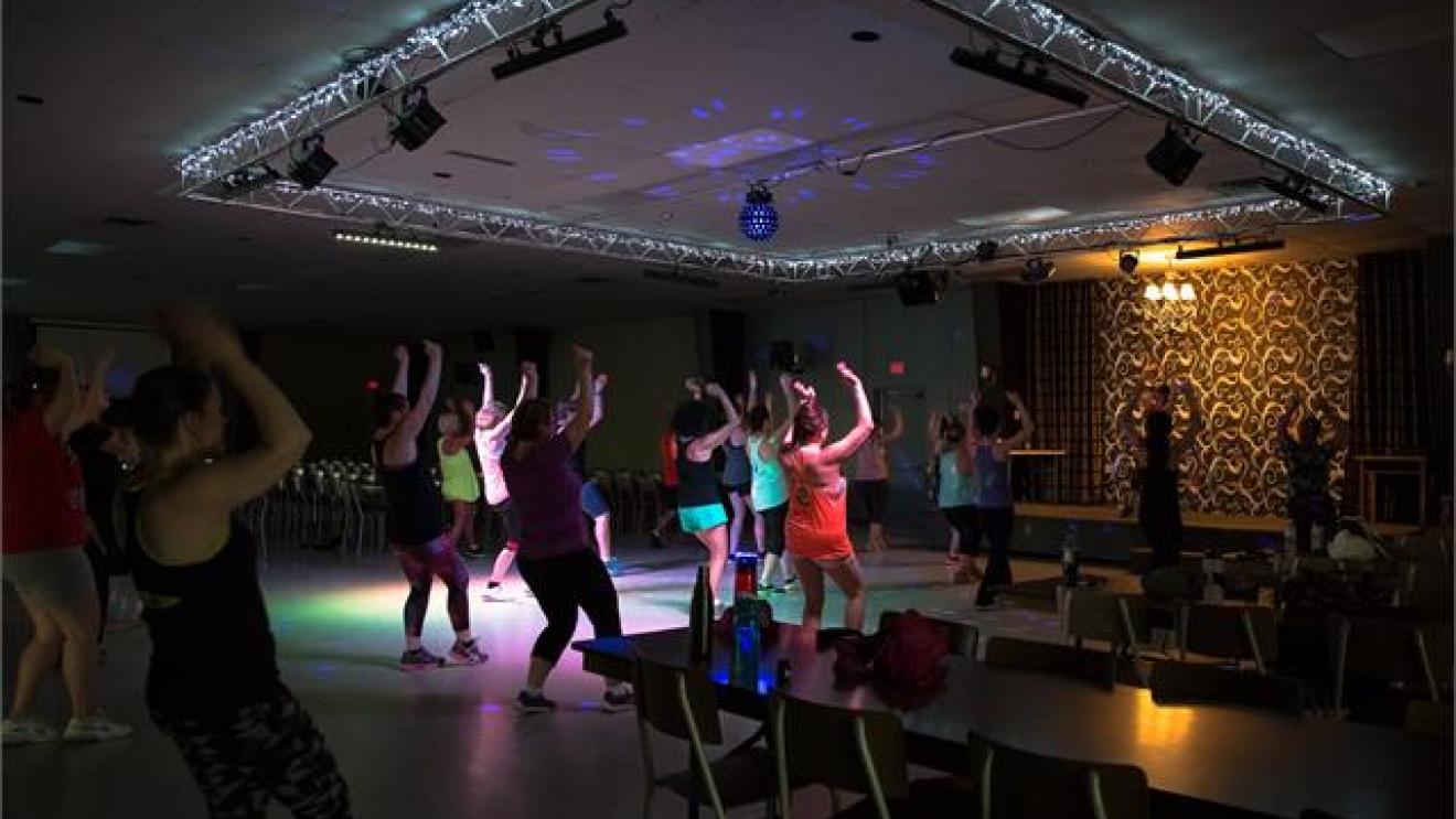 Dance class in a dimly lit room with colorful lights on the ceiling.