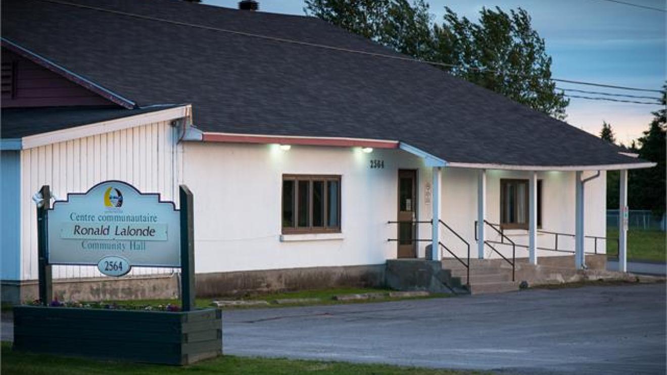 Community center building at dusk with a sign in front.