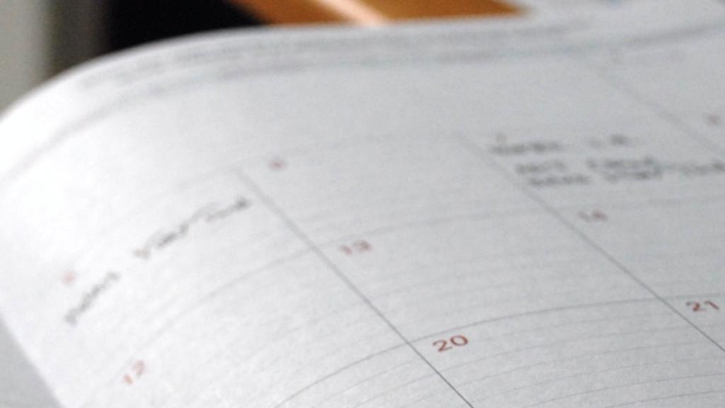 Open planner on a wooden desk, showing a monthly calendar.