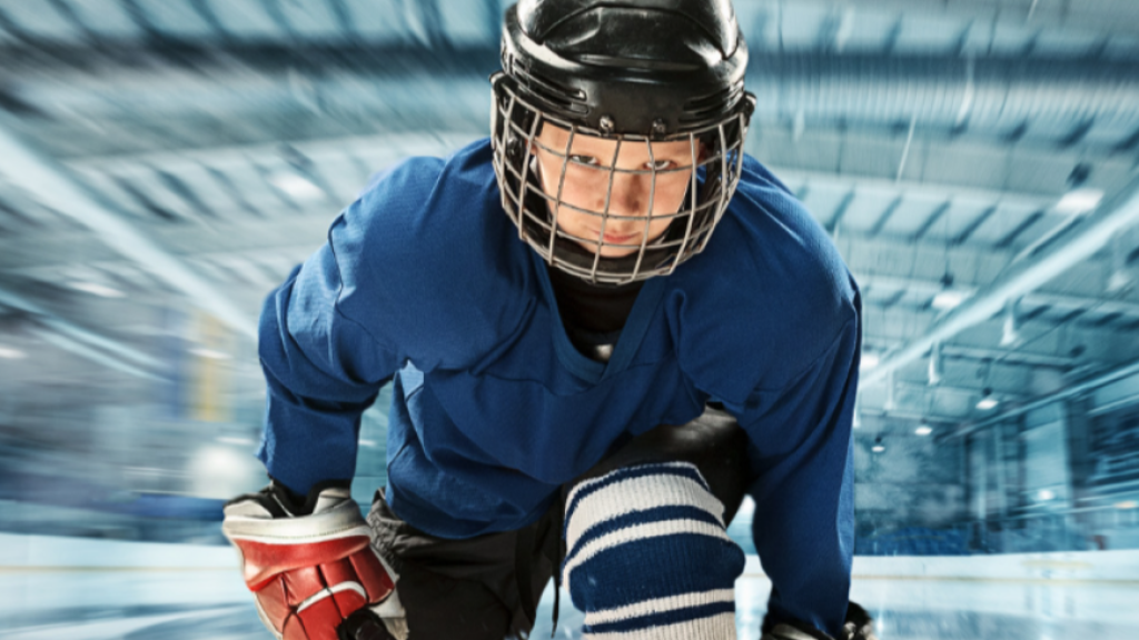 Hockey player in blue jersey skating on ice rink.