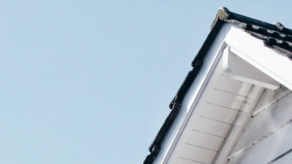 White gable roof with dark shingles against clear blue sky.