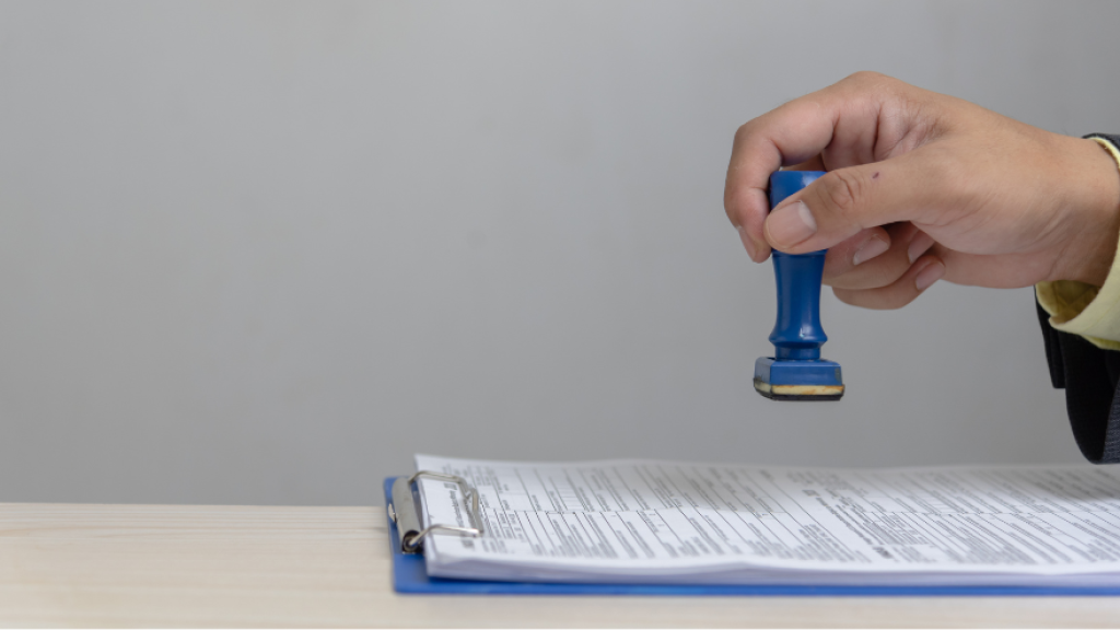 hand holding a stamp over a permit that it is approving