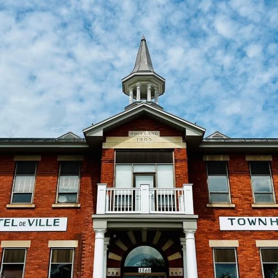 Red brick building with a white steeple under a blue sky.