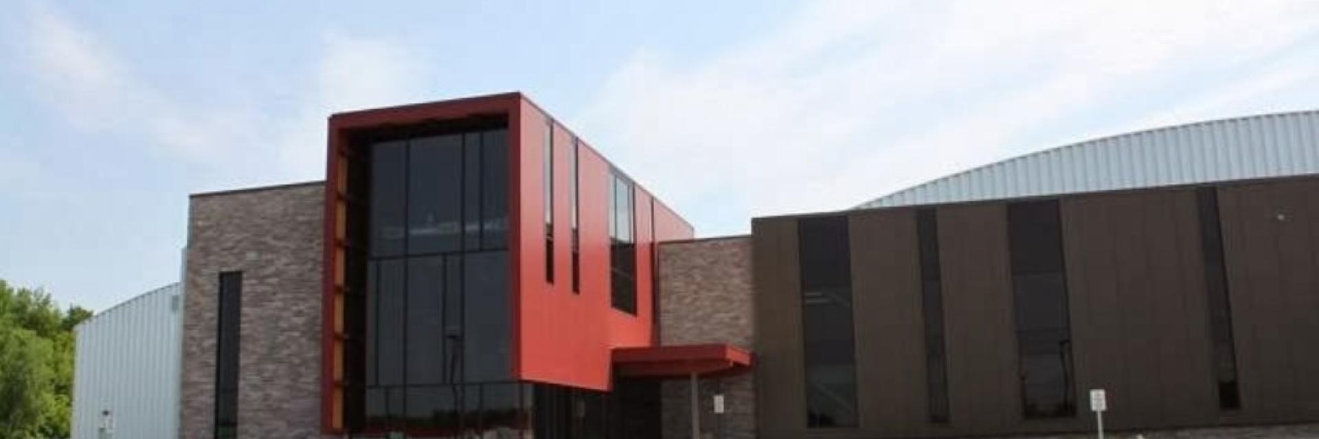 Modern building with red and brown facade under a clear sky.