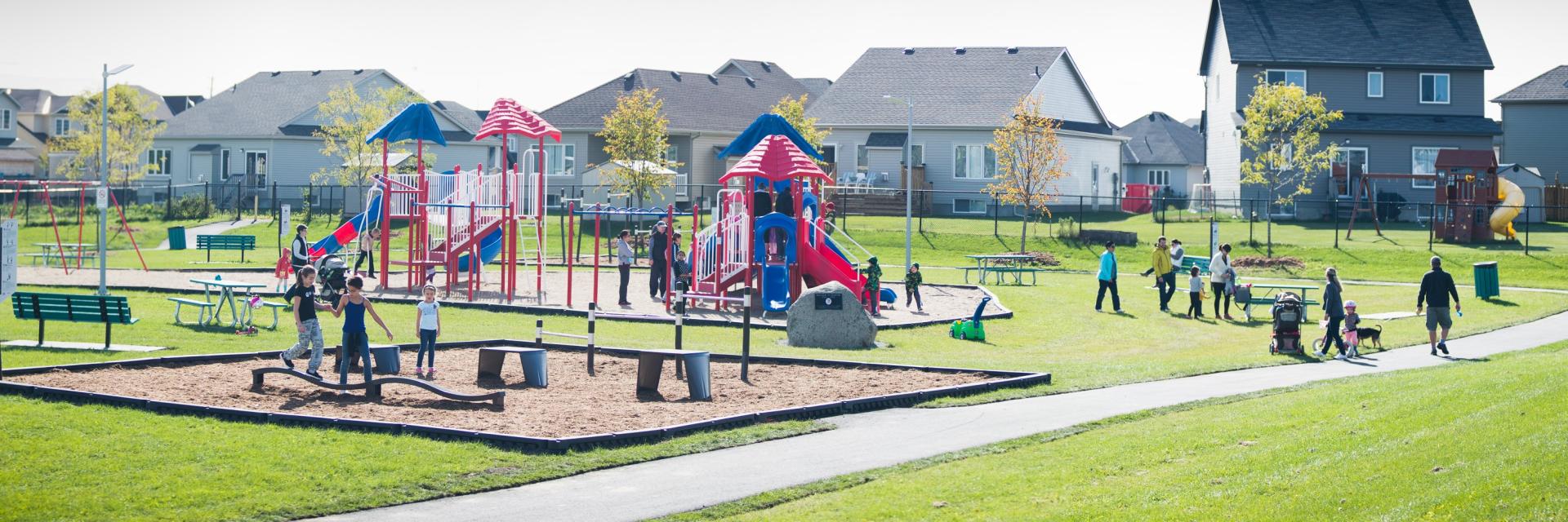 Community park with children playing on colorful playground equipment, sunny day.