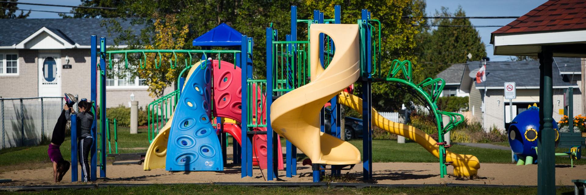 Playground with colourful slides and climbing structures on a sunny day.