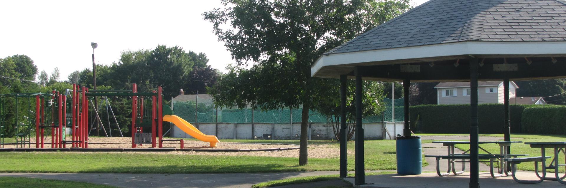Path leading to a pavilion and playground under a sunny sky.