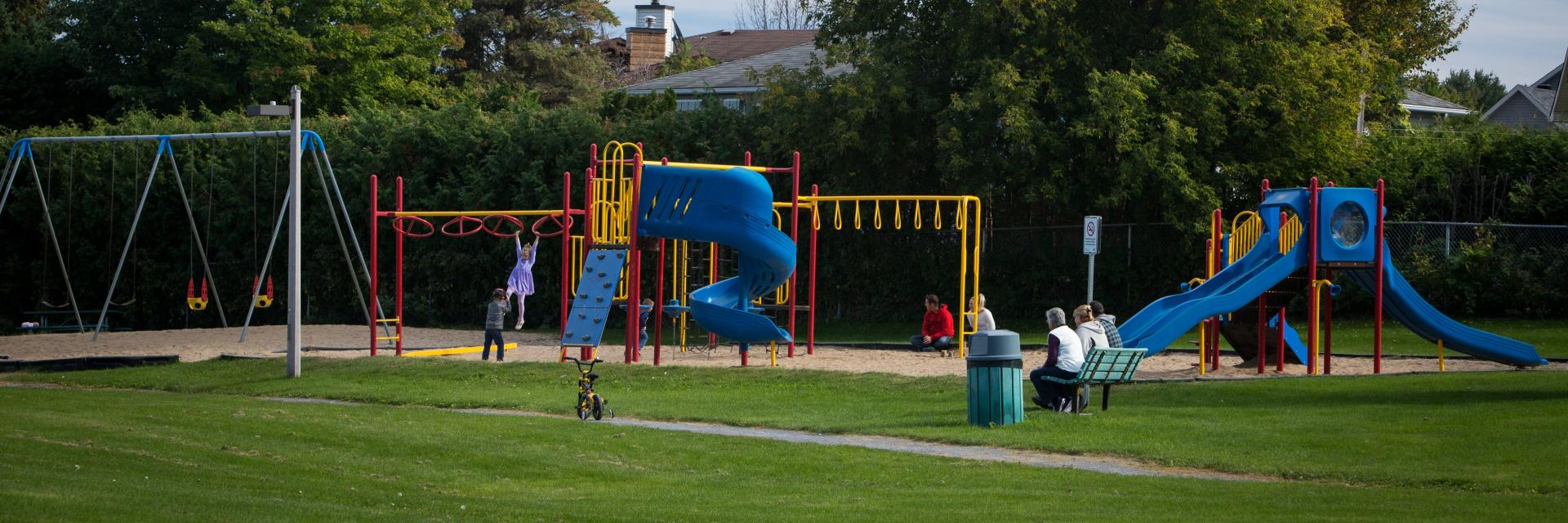 Playground with swings, slides, and children playing on a sunny day.