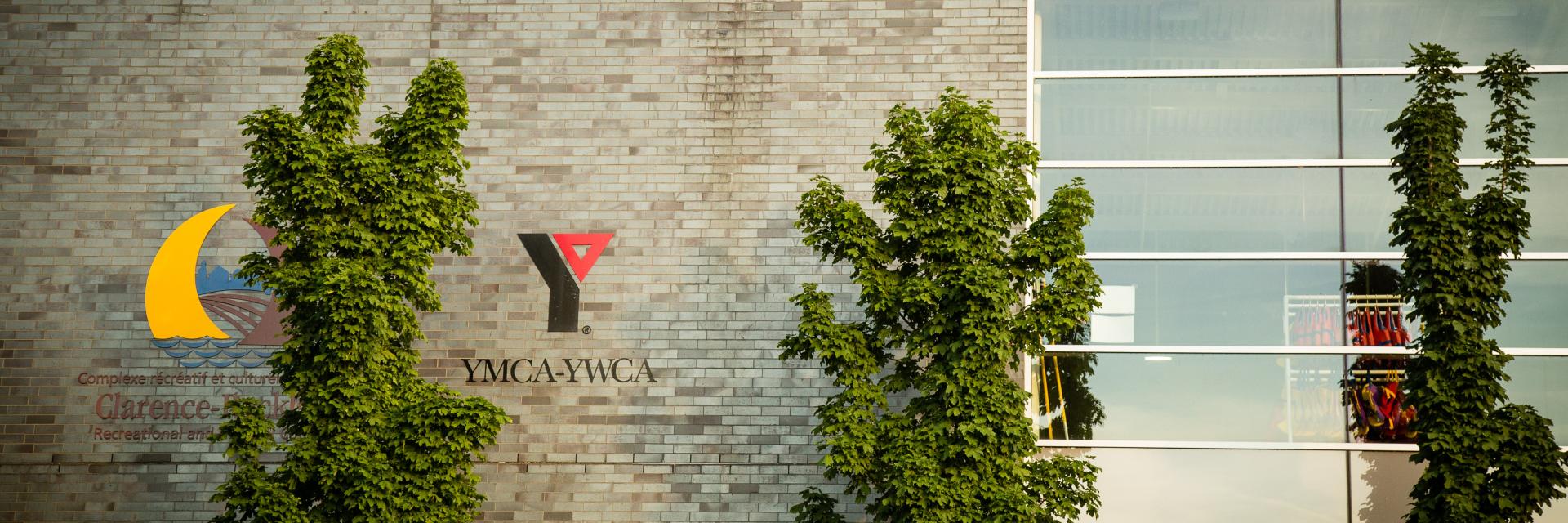 Building facade with green plants and a logo featuring a crescent and red triangle.
