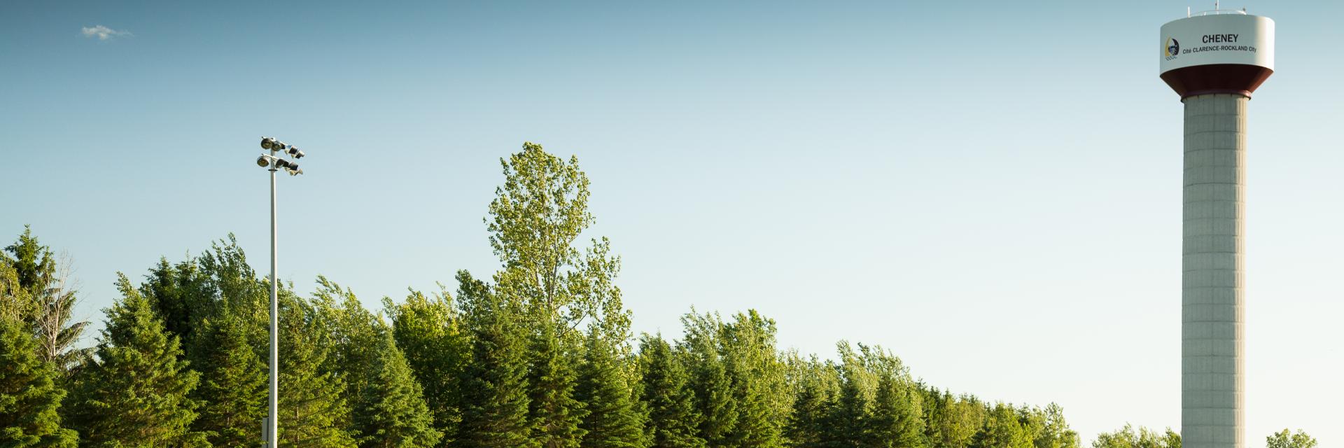 Open field with people, trees, and a tall water tower.
