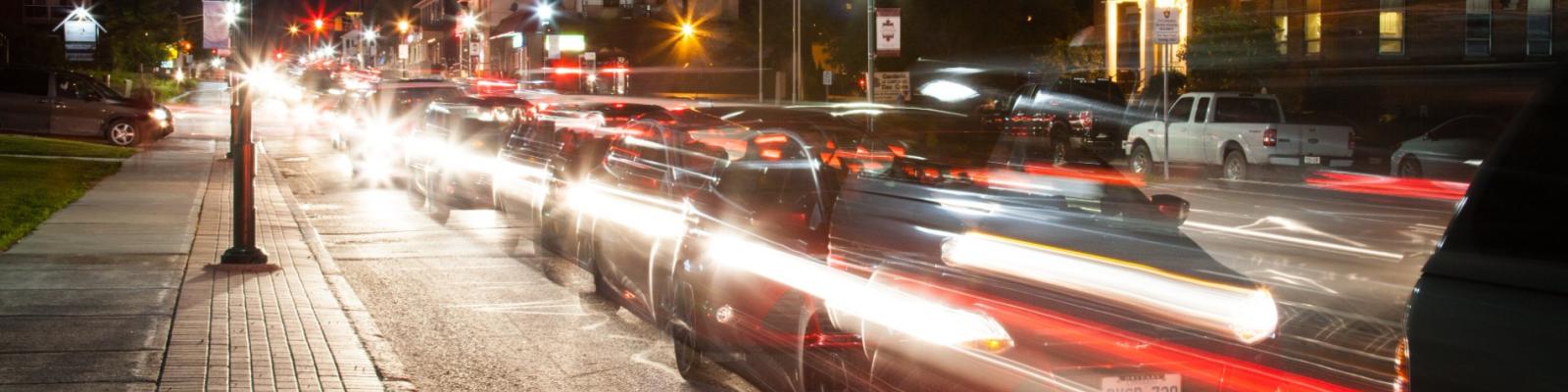 Blurred night traffic with car light trails on a city street.