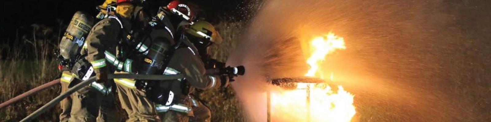 Firefighters extinguishing a blaze at night.