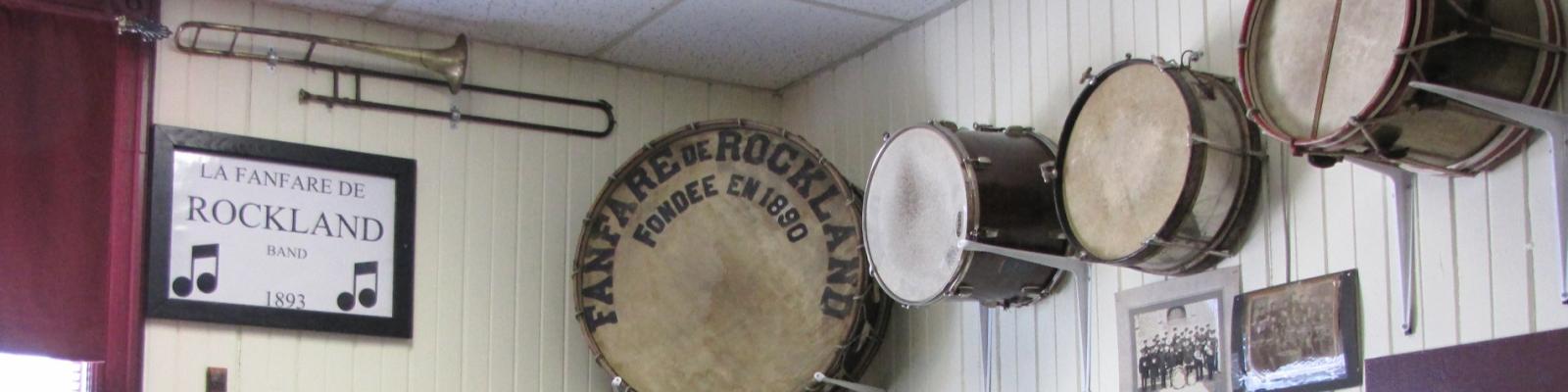 Wall display with drums and a framed band sign.