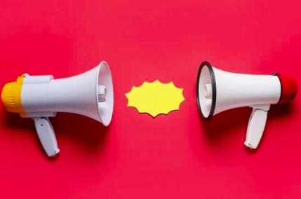 Two megaphones facing each other on a red background with a yellow starburst shape between them.